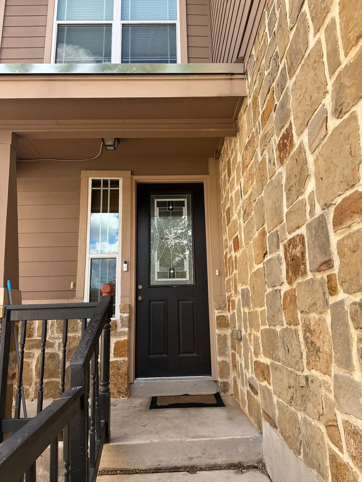 The same front entryway after pressure washing, with brightened stone and clean concrete steps.