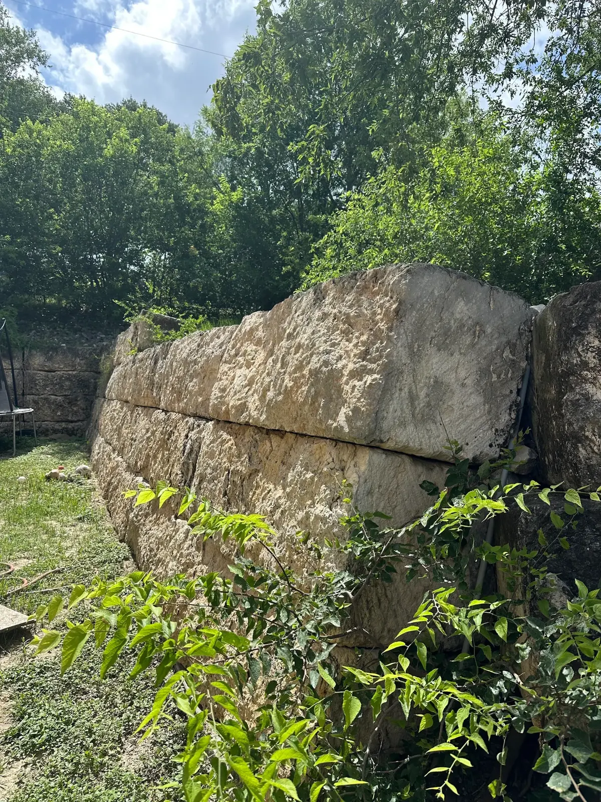 The same corner of the retaining wall after pressure washing, with staining and moss removed.