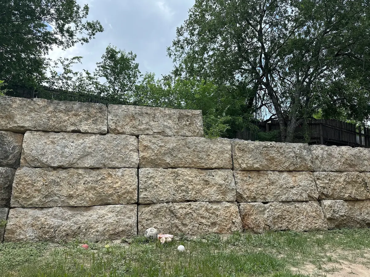 The same limestone retaining wall after pressure washing, with the natural light stone color restored.
